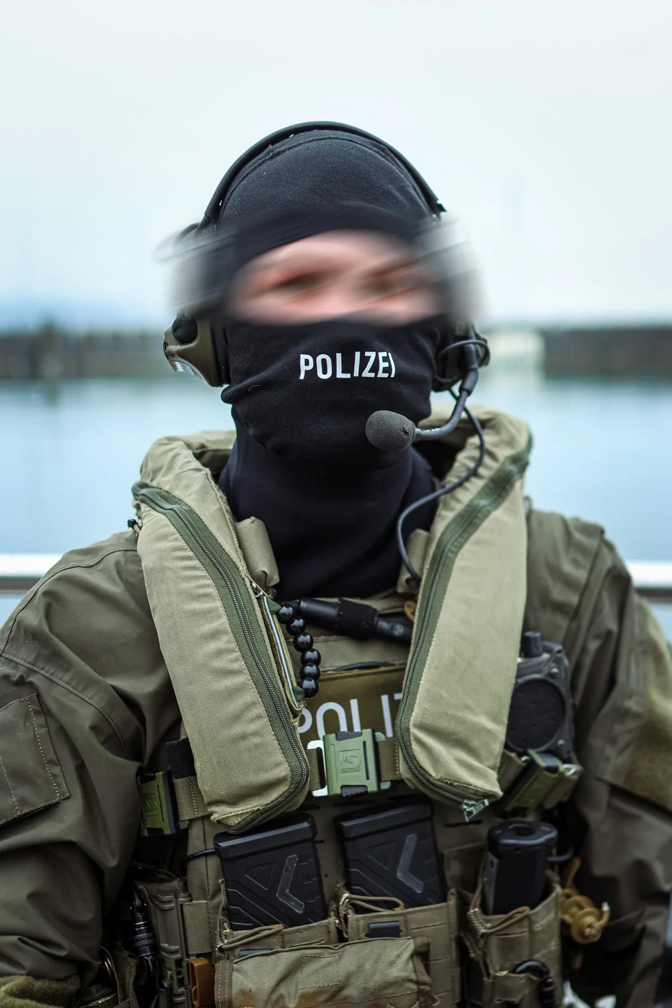 SEK-Beamter in voller taktischer Einsatzausrüstung mit Sturmhaube und Funkgerät