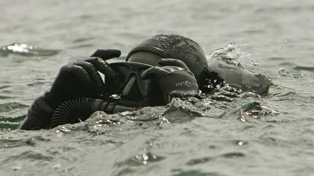 Kampfschwimmer mit Tauchmaske und Kreislaufgerät an der Wasseroberfläche